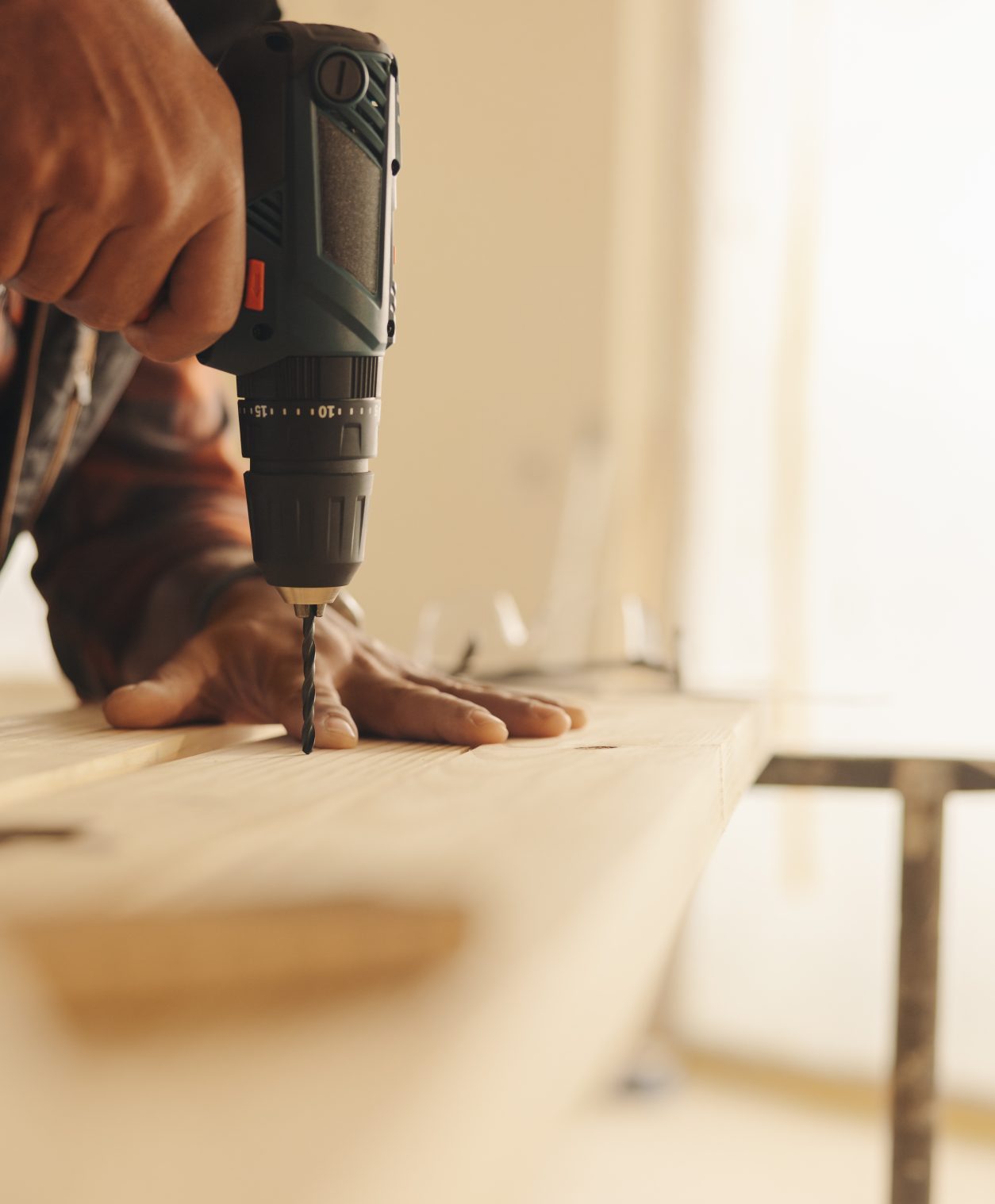 Skilled carpenter uses a drill gun to attach a wooden plank during a home improvement project. The contractor focuses on the kitchen trim work, ensuring a successful renovation and upgrade to the house's interior.